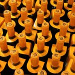 Garrafas de vinho empilhadas em uma adega, com rolhas amarelas visíveis.