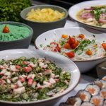 Variedade de pratos da culinária japonesa, incluindo sushi e saladas, servida sobre uma mesa.