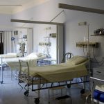 Enfermaria hospitalar ampla com vários leitos vazios e equipamentos médicos.