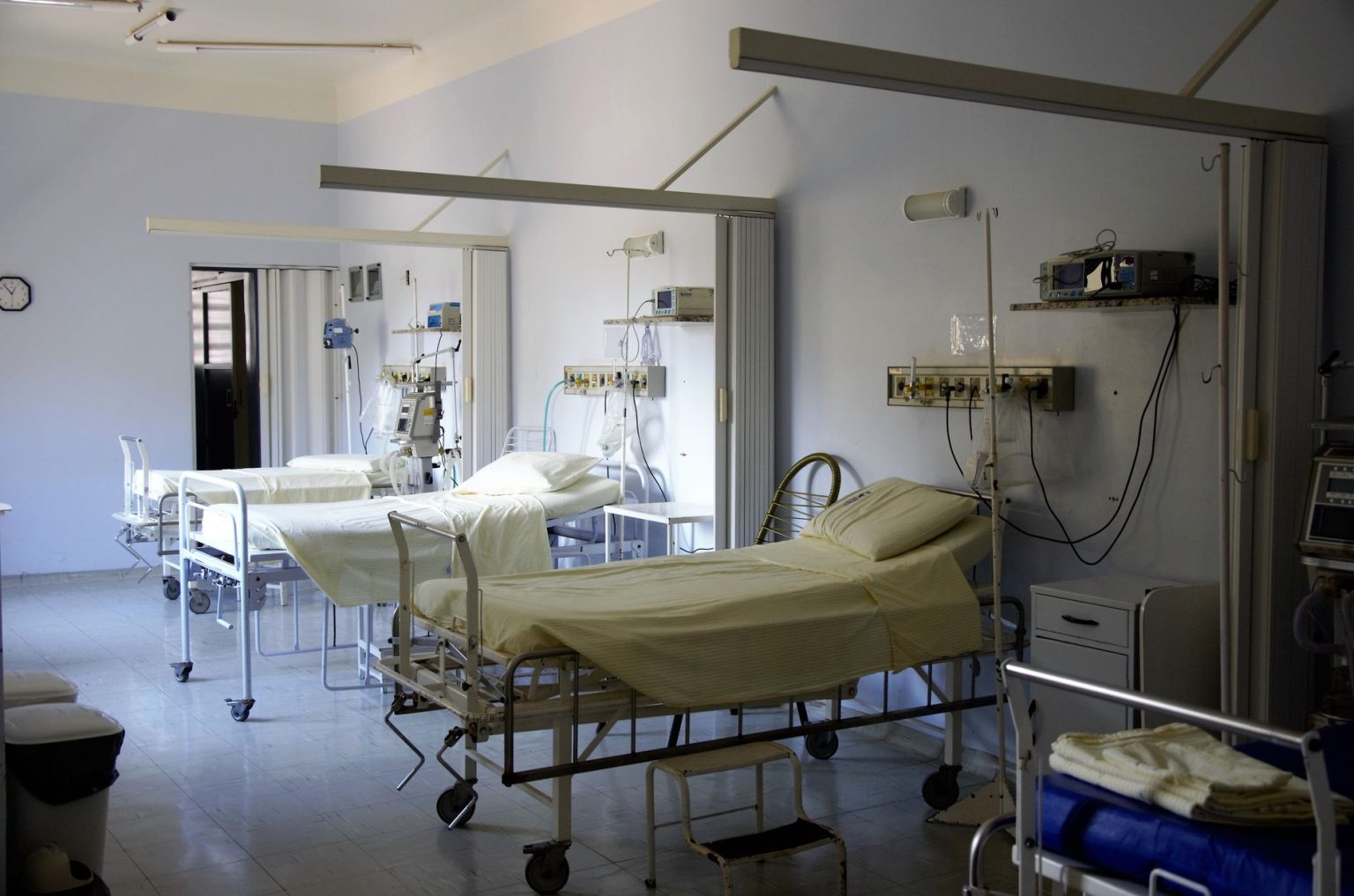 Enfermaria hospitalar ampla com vários leitos vazios e equipamentos médicos.