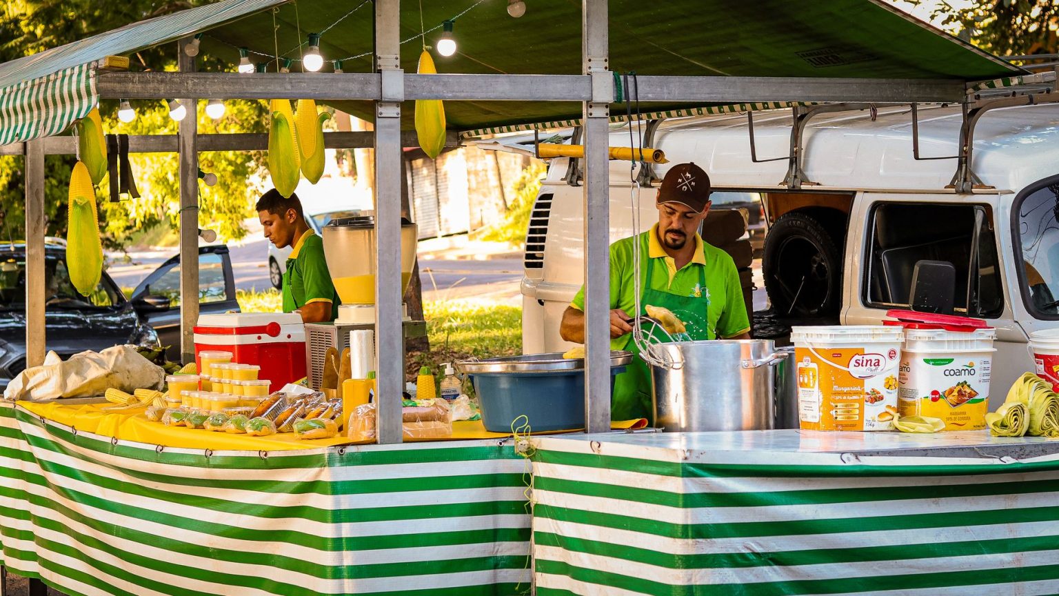 Vendedores preparam pratos à base de milho em uma barraca de comida de rua.