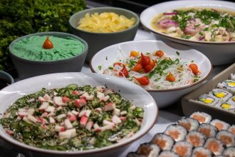 Variedade de pratos da culinária japonesa, incluindo sushi e saladas, servida sobre uma mesa.