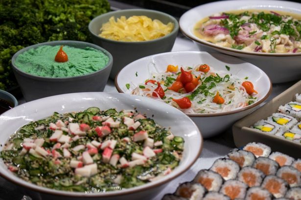 Variedade de pratos da culinária japonesa, incluindo sushi e saladas, servida sobre uma mesa.